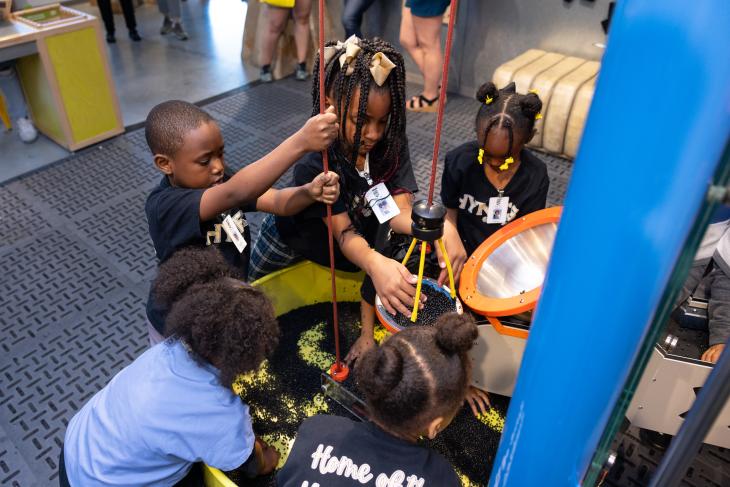 A group of kids interacting with an exhibit at the museum